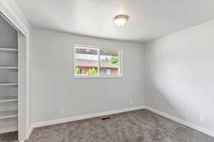 Spare room featuring carpet floors, baseboards, and a textured ceiling