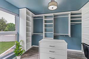 Spacious closet featuring dark wood-style floors and custom shelving