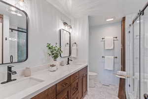 Full bathroom featuring toilet, a stall shower, tile patterned flooring, and double vanity