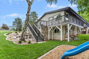Rear view of property featuring a deck, a playground, stairway, and walkout basement