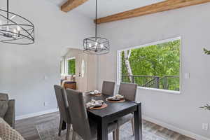 Dining room with a chandelier, beamed ceiling, baseboards, and dark wood-style flooring