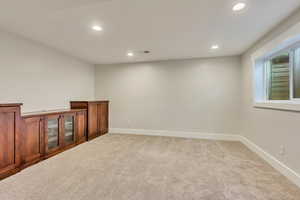 Spare room featuring recessed lighting, light carpet, and baseboards