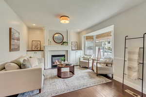 Living area with a tiled fireplace, dark wood finished floors, baseboards, and recessed lighting
