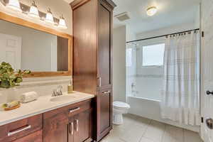 Full bath featuring toilet, shower / tub combo, vanity, and backsplash