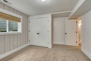 Unfurnished bedroom with carpet floors, baseboards, wallpapered walls, and a closet