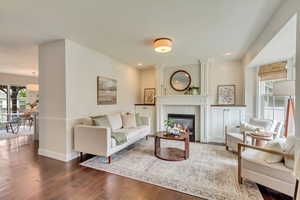 Living area with dark wood-style flooring, a fireplace, baseboards, and recessed lighting