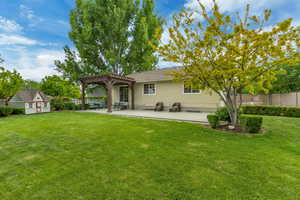 Rear view of house with a pergola, a patio area, and an outbuilding