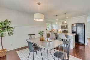 Dining area with a decorative wall, dark wood finished floors, a wainscoted wall, and recessed lighting