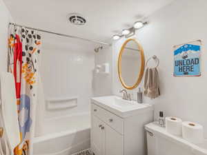 Bathroom featuring shower / bathtub combination with curtain, vanity, and toilet