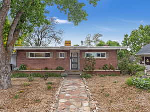 Single story home with a chimney, brick siding, and fence