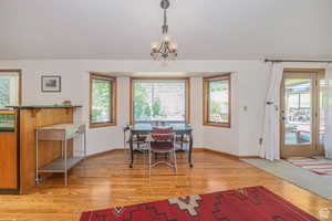 Dining area with baseboards, light wood finished floors, and a chandelier