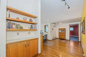 Entryway featuring a baseboard heating unit, an AC wall unit, built in study area, light wood finished floors, and a baseboard radiator