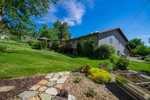 View of green lawn featuring a garden and a deck