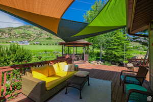 Deck with outdoor lounge area, a mountain view, and a gazebo