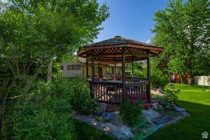 View of green lawn featuring a gazebo and a deck