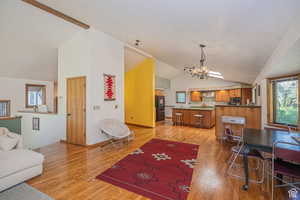 Living area featuring vaulted ceiling, a chandelier, and light wood-type flooring