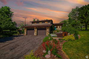 View of front of house featuring stone siding, asphalt driveway, and an attached garage