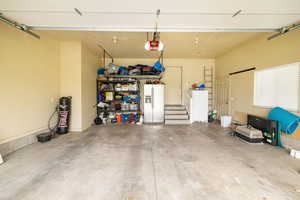 Garage featuring white refrigerator with ice dispenser and a garage door opener