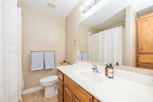 Bathroom with tile patterned floors, toilet, vanity, and baseboards