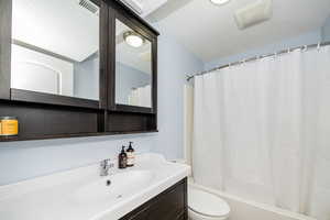 Bathroom with toilet, vanity, and shower / bath combo