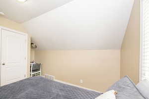 Carpeted bedroom featuring vaulted ceiling, a textured ceiling, and baseboards