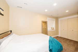 Carpeted bedroom with recessed lighting, baseboards, and a closet