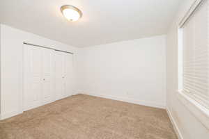 Unfurnished bedroom with carpet flooring, a closet, a textured ceiling, and baseboards