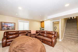 Living room with light carpet, recessed lighting, stairs, baseboards, and a textured ceiling