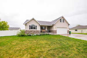 View of front facade featuring stucco siding, concrete driveway, stone siding, and a garage
