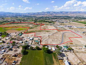 Aerial view of property and surrounding area with property parcel outlined and a mountainous background