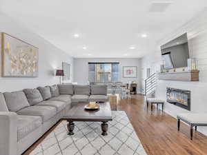 Living room with wood finished floors, recessed lighting, and a glass covered fireplace