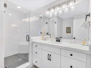 Bathroom with a shower stall, vanity, recessed lighting, and a chandelier