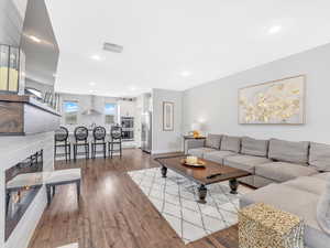 Living room featuring baseboards, wood finished floors, a glass covered fireplace, and recessed lighting