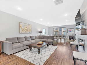 Living area featuring wood finished floors, a glass covered fireplace, and recessed lighting