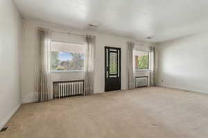 Carpeted empty room with radiator and baseboards