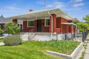 Bungalow featuring brick siding, a chimney, and fence