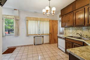 Kitchen with radiator heating unit, a sink, light countertops, a chandelier, and backsplash