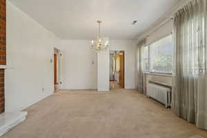 Unfurnished dining area featuring radiator heating unit, a chandelier, light colored carpet, and baseboards