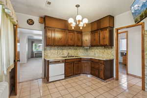 Kitchen with radiator heating unit, dishwasher, a sink, a chandelier, and tasteful backsplash