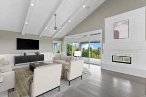 Living room with high vaulted ceiling, a tiled fireplace, wood finished floors, recessed lighting, and a wooden ceiling with exposed beams