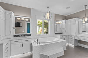Full bath featuring a chandelier, crown molding, a bath, tile patterned floors, and two vanities