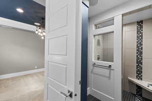 Bathroom with a chandelier, a tile shower, and baseboards