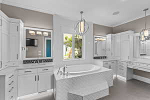 Full bath featuring crown molding, a bath, two vanities, and light tile patterned floors