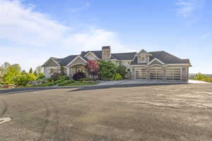 View of front facade featuring stone siding, asphalt driveway, a garage, and a chimney
