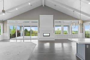 Unfurnished living room featuring a decorative wall, a wainscoted wall, beam ceiling, dark wood-type flooring, and a glass covered fireplace