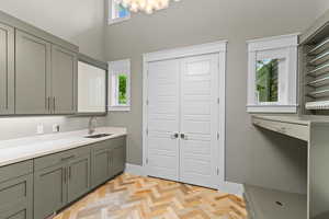 Clothes washing area featuring a sink, healthy amount of natural light, a towering ceiling, baseboards, and a chandelier