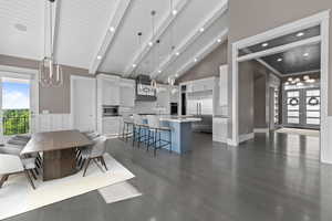 Dining space with beamed ceiling, dark wood-type flooring, high vaulted ceiling, french doors, and recessed lighting