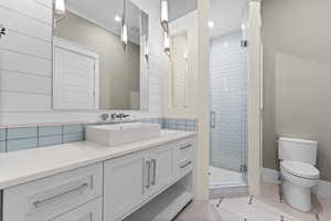 Bathroom with a shower stall, toilet, vanity, tile patterned flooring, and recessed lighting