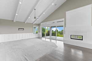 Unfurnished living room with a tile fireplace, beam ceiling, high vaulted ceiling, wood finished floors, and recessed lighting