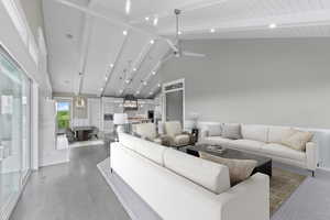 Living room with high vaulted ceiling, beamed ceiling, wood finished floors, and a ceiling fan
